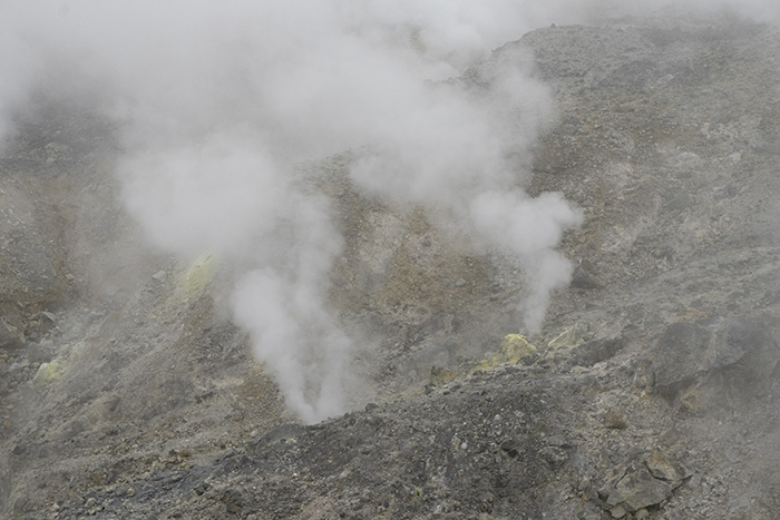 山道すぐ脇の火口。硫黄ガスが岩の隙間から噴出している