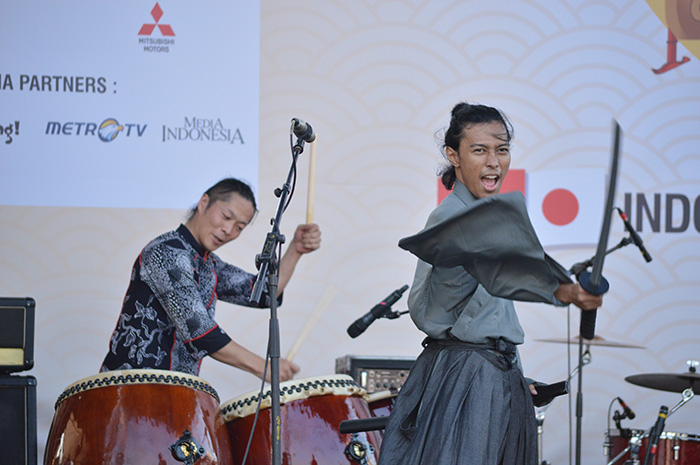 プロ和太鼓奏者の小川大介さん(左)とインドネシア人大学生らによる日本語ミュージカル劇団「en塾」の剣舞のコラボレーション=坂田写す