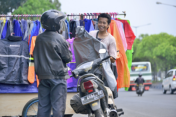 大通り彩る雨がっぱ　雨期のバイクの必需品