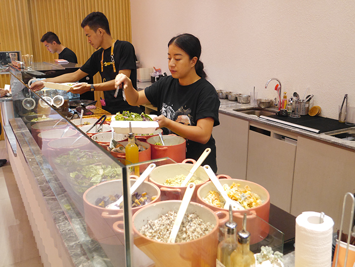 持ち帰り用の箱に毎朝仕入れている野菜を詰めるカレイカさん(真ん中)